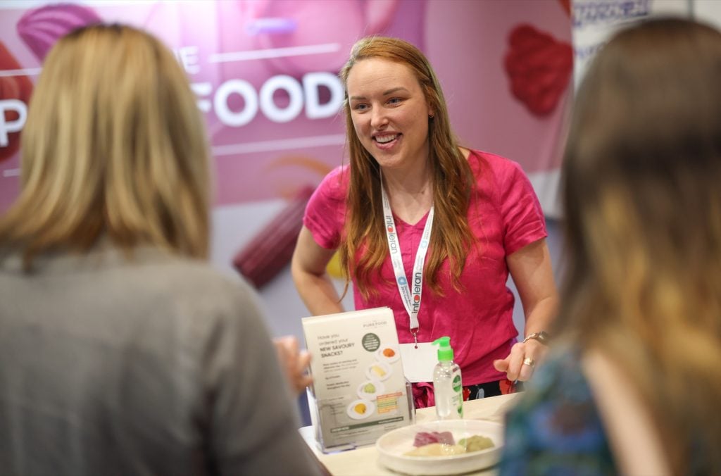 An exhibitor speaking with two delegates at the 2024 conference exhibition